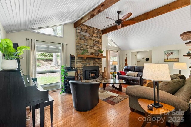 living area with light wood-type flooring, lofted ceiling with beams, a ceiling fan, and plenty of natural light
