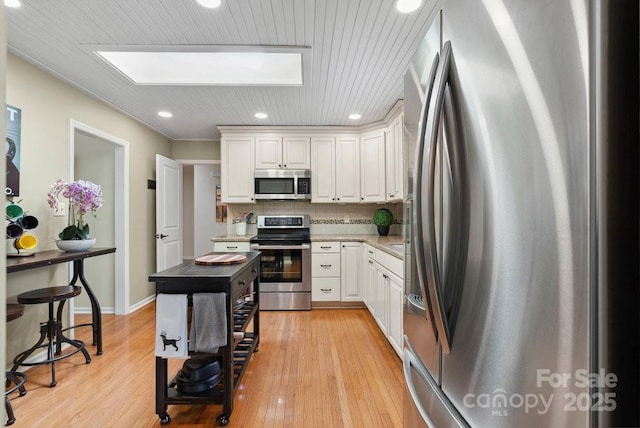 kitchen featuring recessed lighting, stainless steel appliances, light wood-style floors, backsplash, and white cabinetry