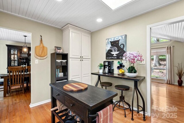 dining space with wooden ceiling, light wood-style flooring, and baseboards