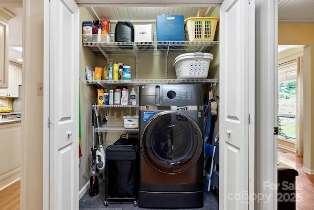 washroom featuring wood finished floors, washer / clothes dryer, laundry area, and baseboards