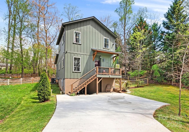 view of front of house with driveway, stairway, a deck, board and batten siding, and a front yard