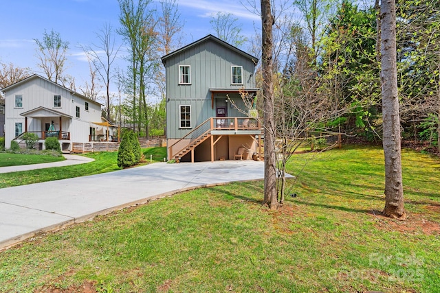 view of front of home featuring board and batten siding, driveway, a front yard, and stairway