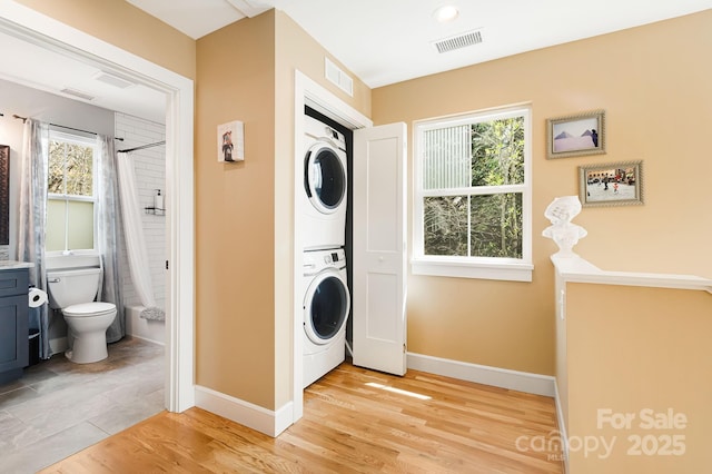 laundry room featuring stacked washer / dryer, visible vents, and plenty of natural light