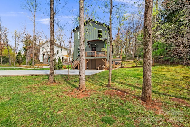 view of front of property featuring stairs, board and batten siding, driveway, a front yard, and a deck