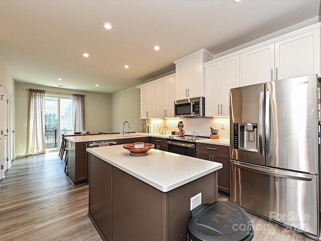 kitchen with recessed lighting, appliances with stainless steel finishes, white cabinetry, a center island, and a peninsula