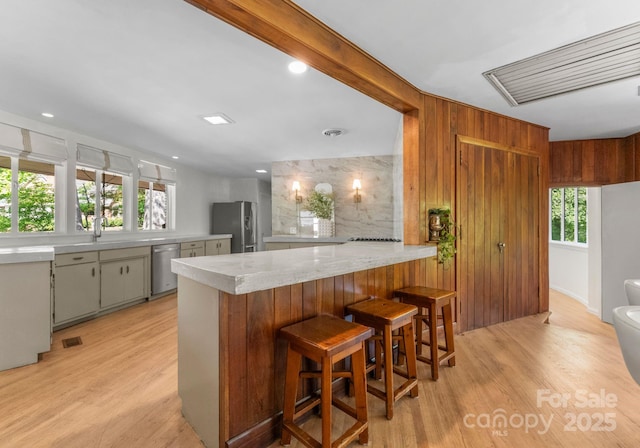 916 E Park Dr, Lincolnton, NC 28092 - kitchen with appliances with stainless steel finishes, light wood-type flooring, a peninsula, a kitchen bar, and wooden walls