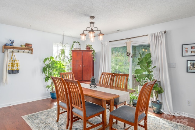 dining room featuring baseboards, a textured ceiling, and wood finished floors