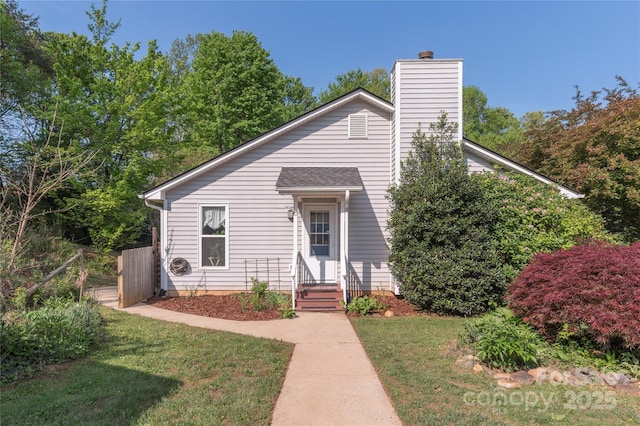 view of front of property featuring fence, a chimney, and a front yard