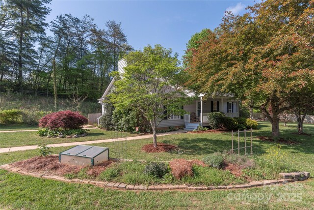 view of front of home featuring covered porch, a chimney, and a front lawn