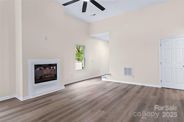 unfurnished living room with ceiling fan, visible vents, and wood finished floors