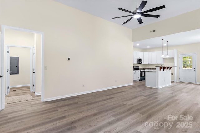 unfurnished living room featuring baseboards, light wood-style flooring, and ceiling fan