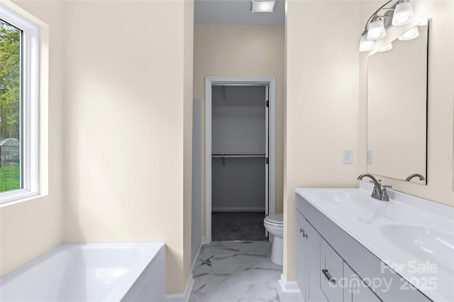 full bathroom with a walk in closet, a sink, toilet, marble finish floor, and a bath