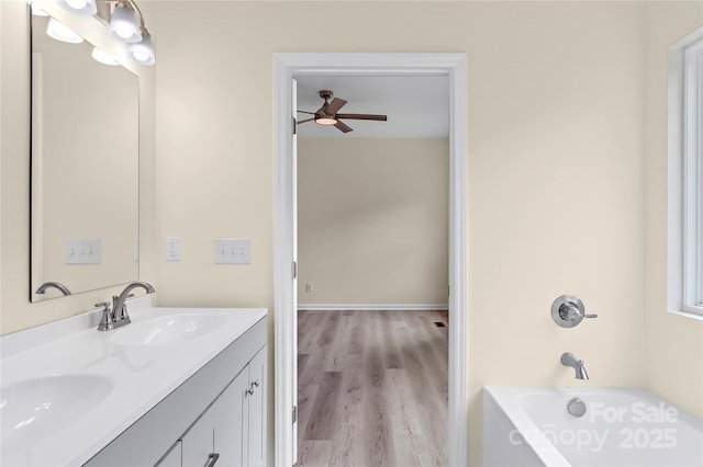 full bathroom featuring double vanity, ceiling fan, a sink, and wood finished floors