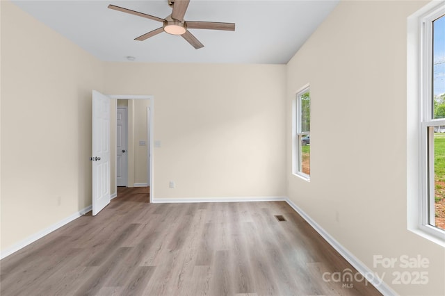 empty room featuring baseboards, ceiling fan, and light wood finished floors