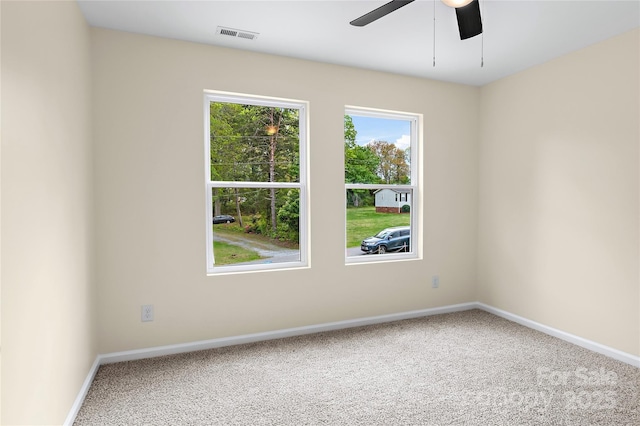 carpeted empty room with baseboards, ceiling fan, and visible vents
