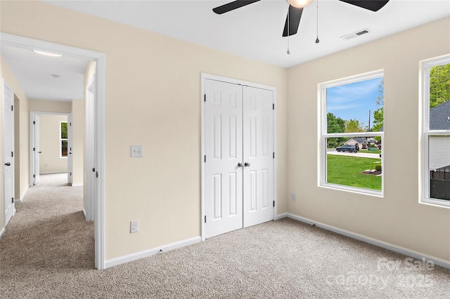 unfurnished bedroom with ceiling fan, carpet floors, baseboards, visible vents, and a closet