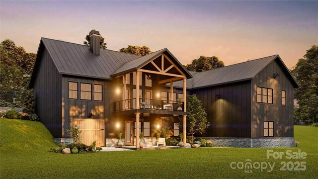 back of property at dusk with metal roof, a lawn, a chimney, and a balcony