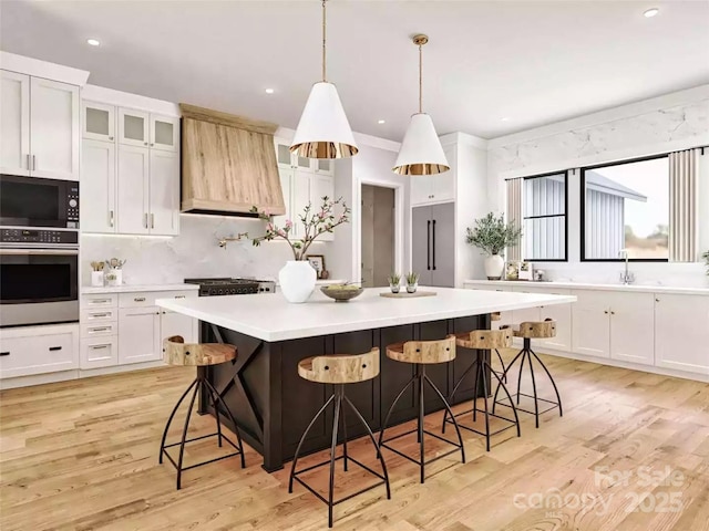 kitchen featuring light countertops, built in appliances, white cabinets, a large island, and premium range hood