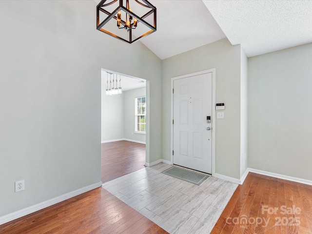 entryway with a notable chandelier, hardwood / wood-style floors, and baseboards