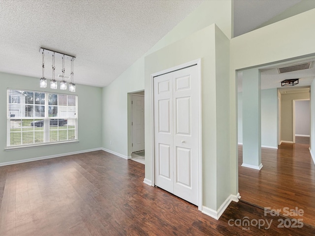 unfurnished dining area featuring visible vents, baseboards, a textured ceiling, lofted ceiling, and dark wood finished floors