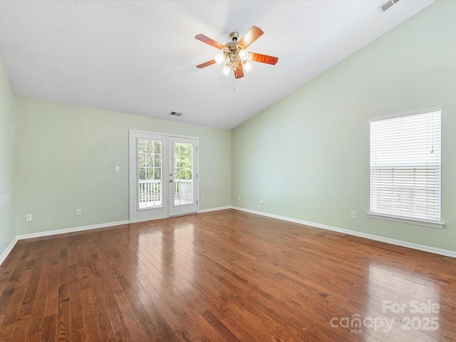 spare room with lofted ceiling, visible vents, baseboards, wood finished floors, and a ceiling fan