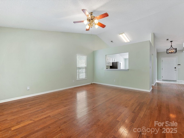 unfurnished living room with lofted ceiling, wood finished floors, ceiling fan, and baseboards