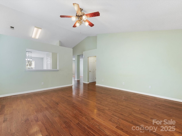 spare room with visible vents, vaulted ceiling, baseboards, wood finished floors, and ceiling fan with notable chandelier