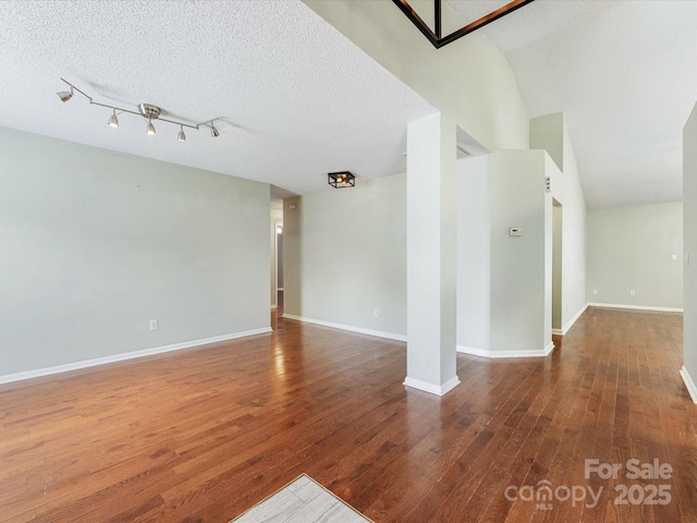 empty room featuring baseboards, a textured ceiling, and wood-type flooring
