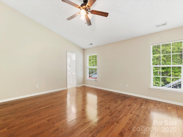 spare room featuring wood finished floors, visible vents, ceiling fan, and baseboards