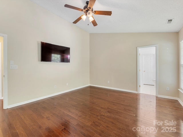 empty room with wood finished floors, ceiling fan, visible vents, and baseboards