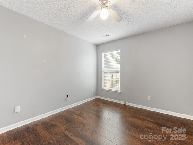 unfurnished room with a textured ceiling, visible vents, baseboards, dark wood finished floors, and a ceiling fan