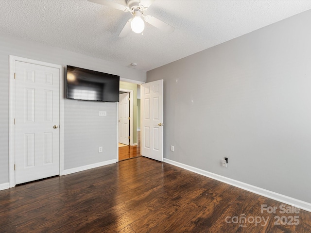 unfurnished bedroom with a textured ceiling, wood finished floors, and baseboards