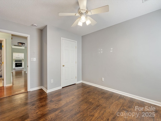 unfurnished bedroom with a textured ceiling, wood finished floors, a ceiling fan, and baseboards