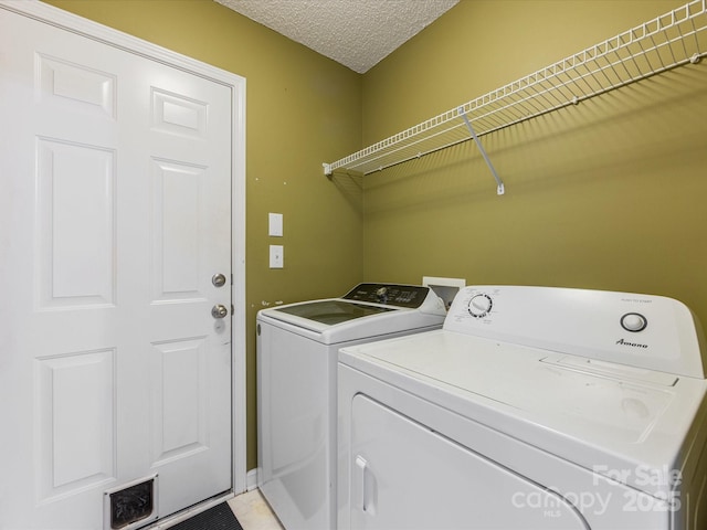 clothes washing area with washer and dryer, visible vents, laundry area, and a textured ceiling