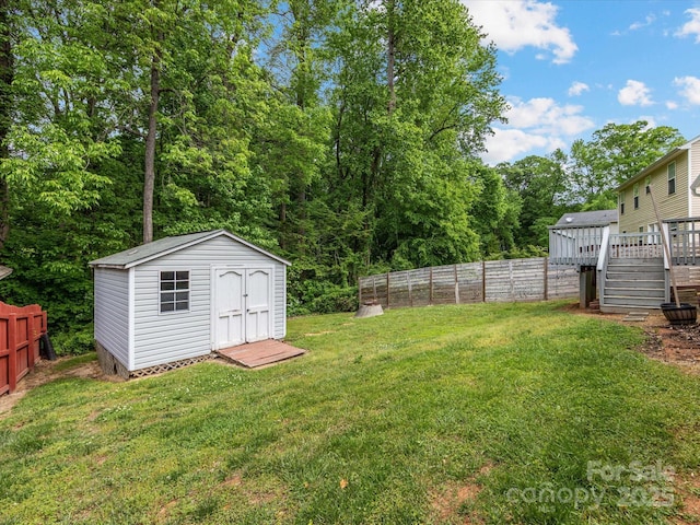 view of yard with a storage shed, a deck, an outdoor structure, and a fenced backyard