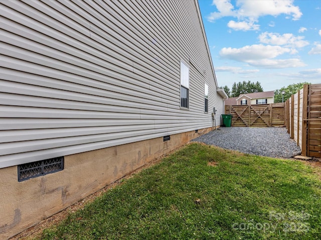 view of side of property featuring a lawn, fence, a gate, and crawl space