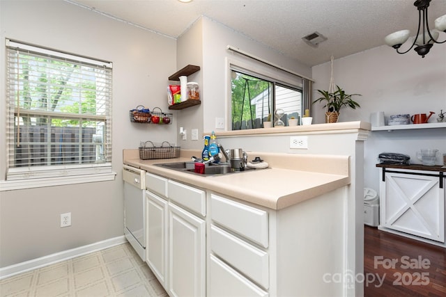 1766 Forest Side Ln, Charlotte, NC 28213 - kitchen featuring white cabinets, white dishwasher, open shelves, an inviting chandelier, and light countertops