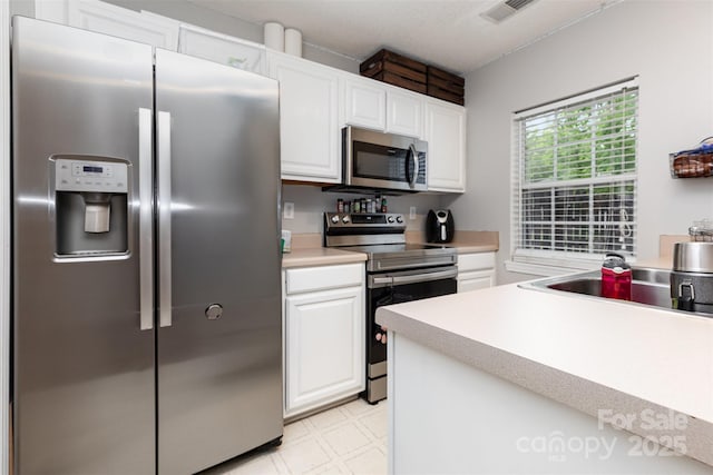 1766 Forest Side Ln, Charlotte, NC 28213 - kitchen featuring white cabinets, appliances with stainless steel finishes, light countertops, light floors, and visible vents