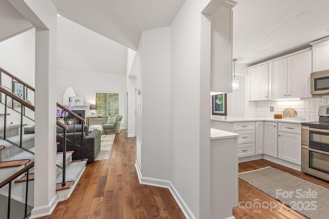 9012 Saint Thomas Ln, Charlotte, NC 28277 - kitchen with dark wood-style flooring, light countertops, appliances with stainless steel finishes, white cabinetry, and backsplash