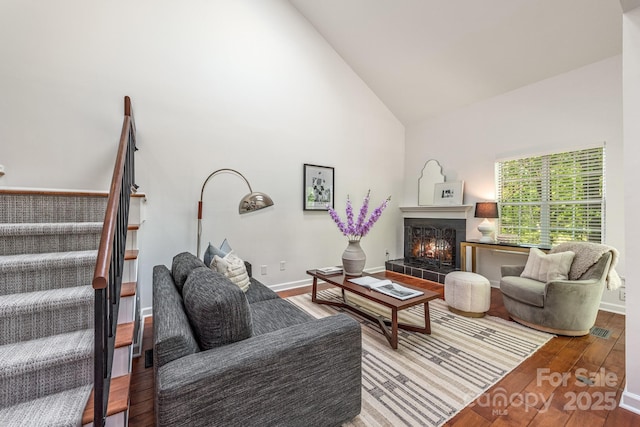 9012 Saint Thomas Ln, Charlotte, NC 28277 - living room with stairs, visible vents, high vaulted ceiling, a tile fireplace, and wood finished floors