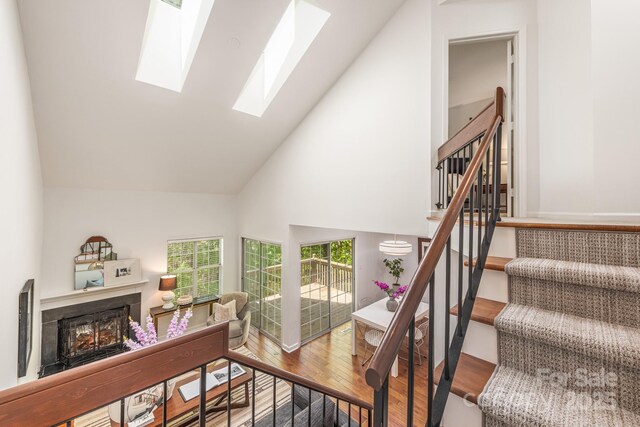 9012 Saint Thomas Ln, Charlotte, NC 28277 - stairway with a warm lit fireplace, a skylight, high vaulted ceiling, and wood finished floors