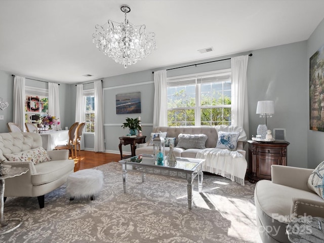 living area with plenty of natural light, wood finished floors, visible vents, and a chandelier