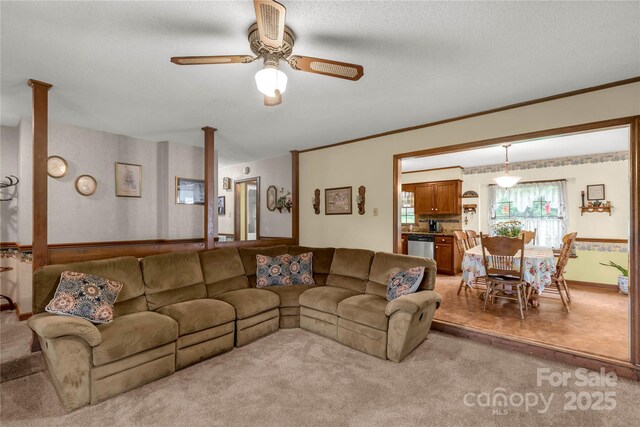 living room with baseboards, a ceiling fan, light carpet, and a textured ceiling