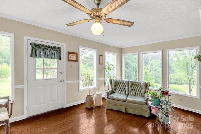 sunroom / solarium with wood finished floors, a textured ceiling, baseboards, and a healthy amount of sunlight