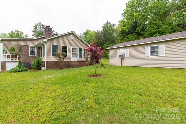 exterior space featuring a front lawn, central AC, and a chimney