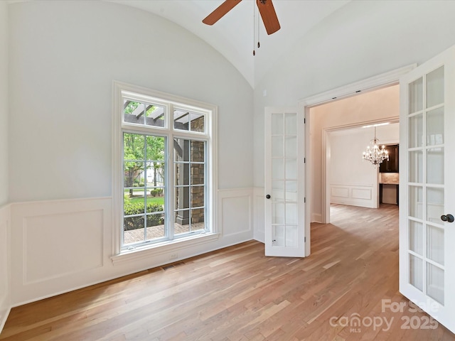empty room with light wood-style floors, visible vents, a wainscoted wall, and french doors
