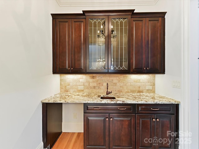 bar featuring bar, backsplash, baseboards, and light wood-style flooring