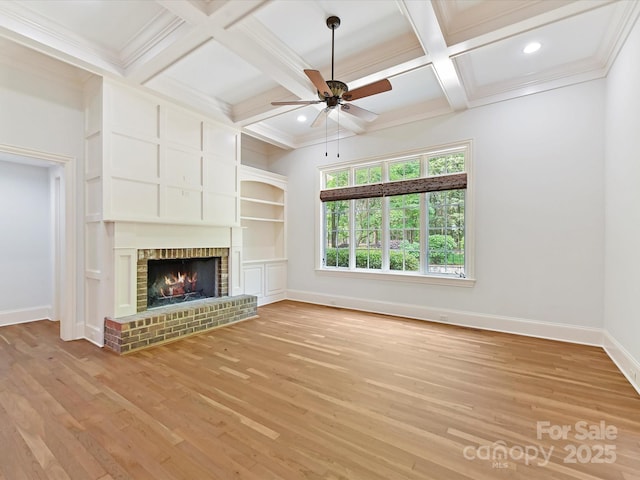 unfurnished living room with a ceiling fan, coffered ceiling, light wood finished floors, a fireplace, and baseboards