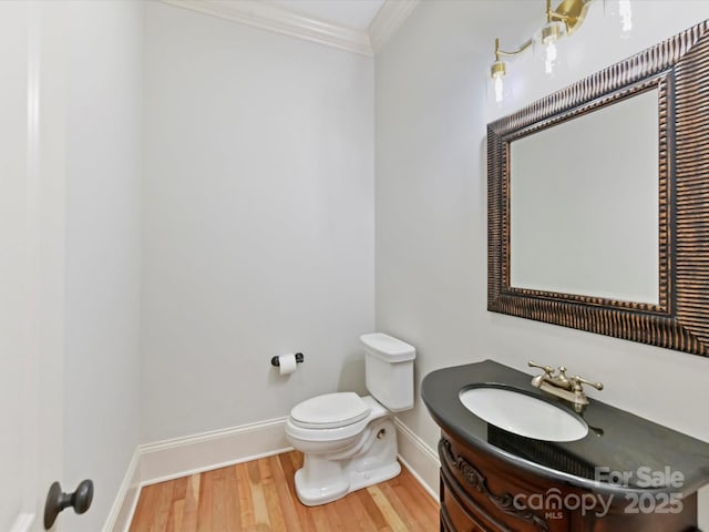 bathroom with crown molding, wood finished floors, vanity, baseboards, and toilet
