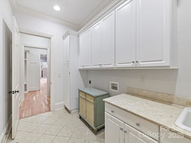 washroom featuring ornamental molding, light tile patterned floors, hookup for an electric dryer, hookup for a washing machine, and cabinet space